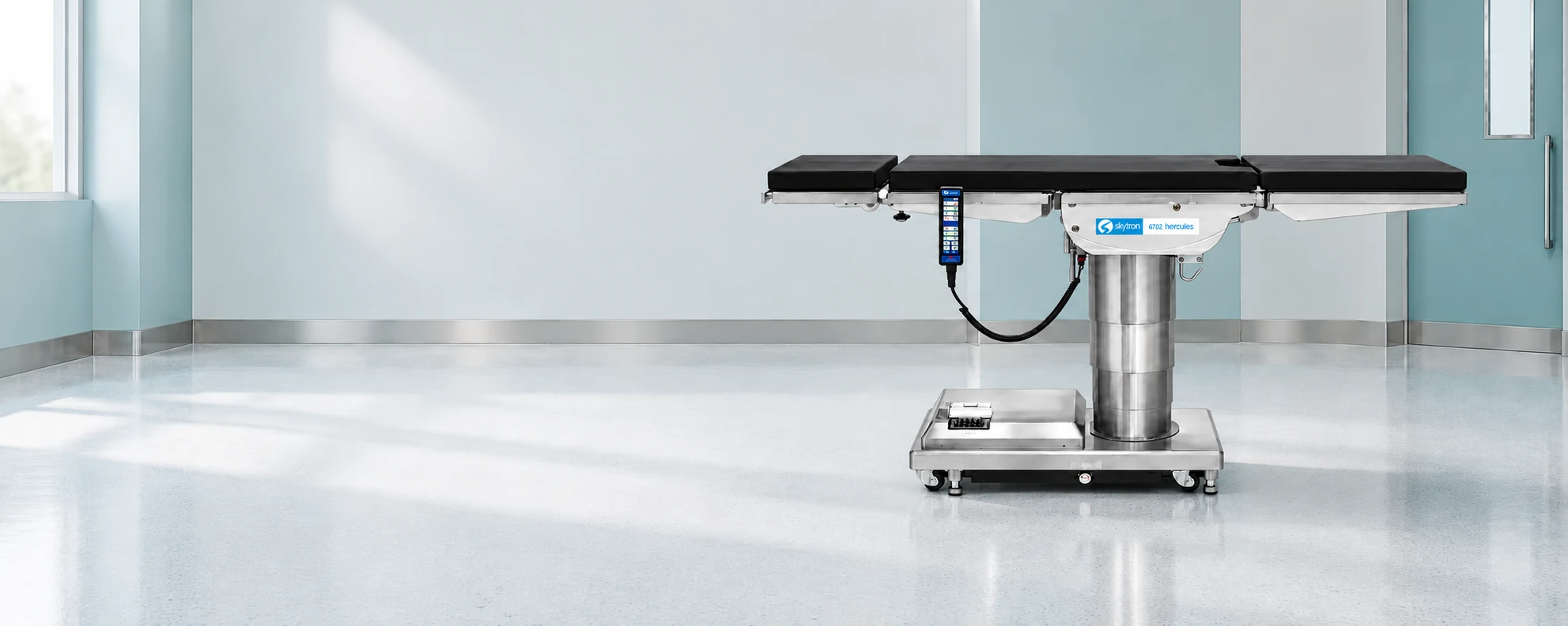 Product render of the Skytron 6702 Hercules surgical table with black segmented pads, a stainless-steel pedestal and low wheeled base, and a wired hand controller in an illustrative operating room.
